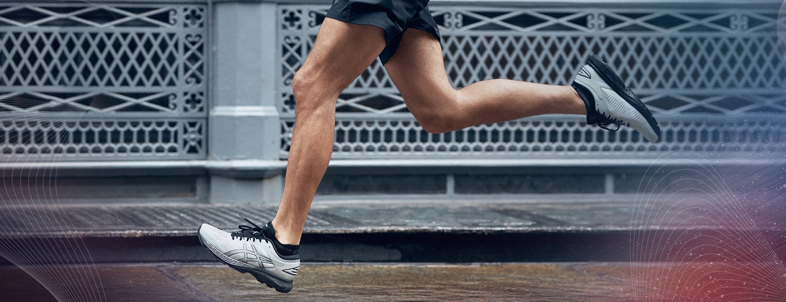 Closeup of the legs of a man running in shorts and white shoes.