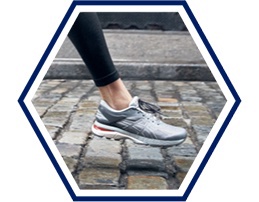 Closeup of a woman’s foot mid-stride in gray running shoes.