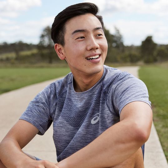 An Asian male model/runner takes a rest outside and smiles naturally 