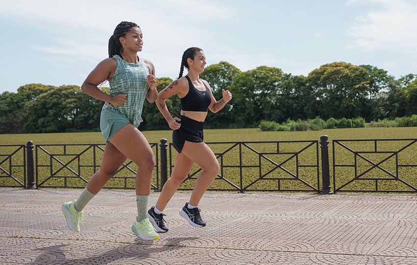 Two female runners running through the city on the sidewalk wearing the Gel-Kayano™ 31