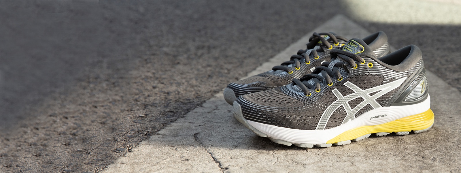 Grey and yellow running shoes sitting on a street