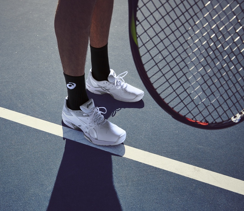 feet and racket on tennis court