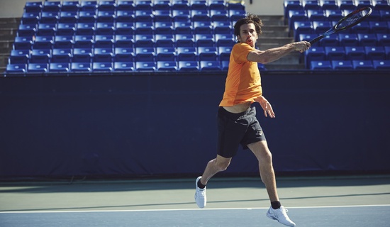 man in orange t shirt playing tennis