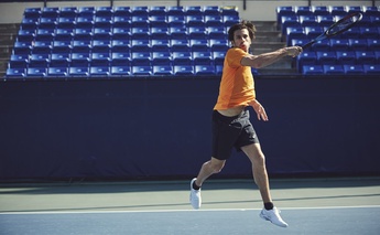 man in orange t shirt playing tennis