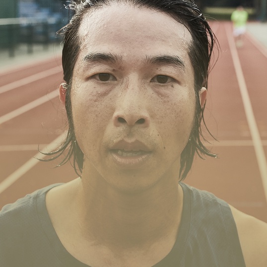 Close up of a man's face while he is standing on a track after running 