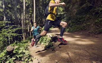 man & woman trail running - turning a corner; woman in teal shirt; man in yellow shirt