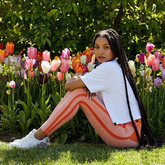 Woman sitting in front of tulips in ASICS sportstyle footwear and apparel.  