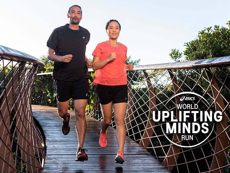 Male and female athletes running across a wooden planked bridge. ASICS World Uplifting Minds Run logo in white. 