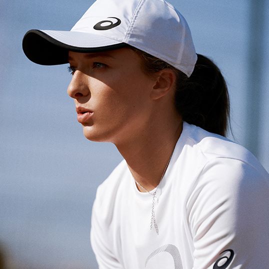 Female tennis player in white ASICS hat and tshirt.