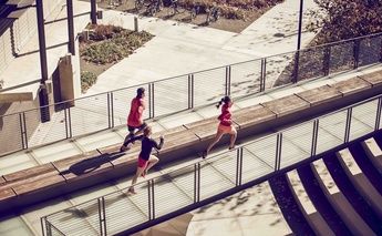 two women & 1 man running across a bridge - top view