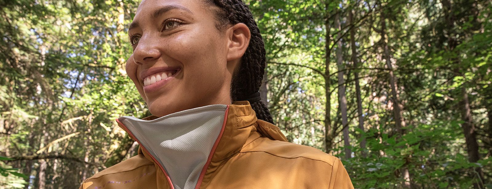 Woman wearing sustainable ASICS apparel smiling in the forest.