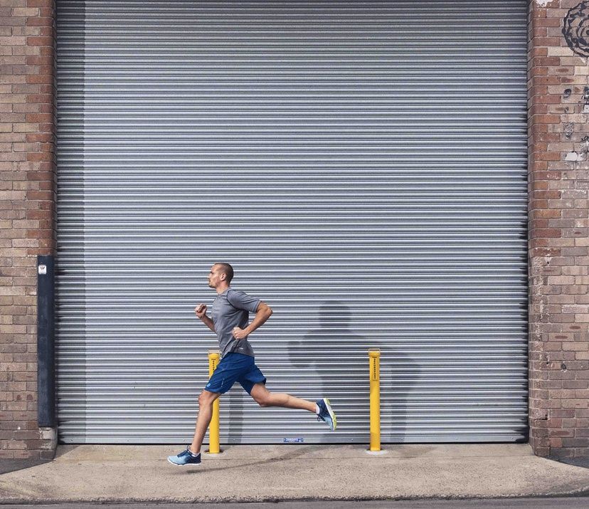 man running on streets; warehouse metal slidding door behind him
