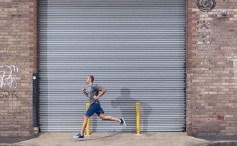man running on streets; warehouse metal slidding door behind him