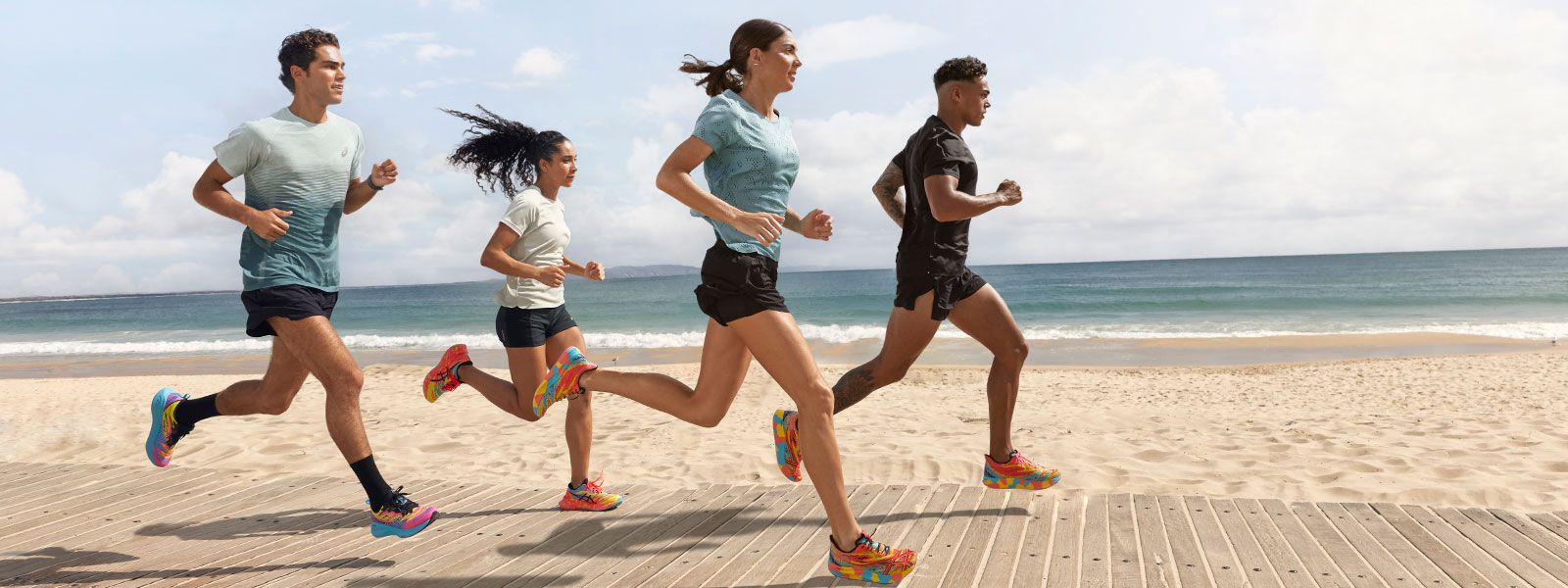 Group of people running together on a beach boardwalk.