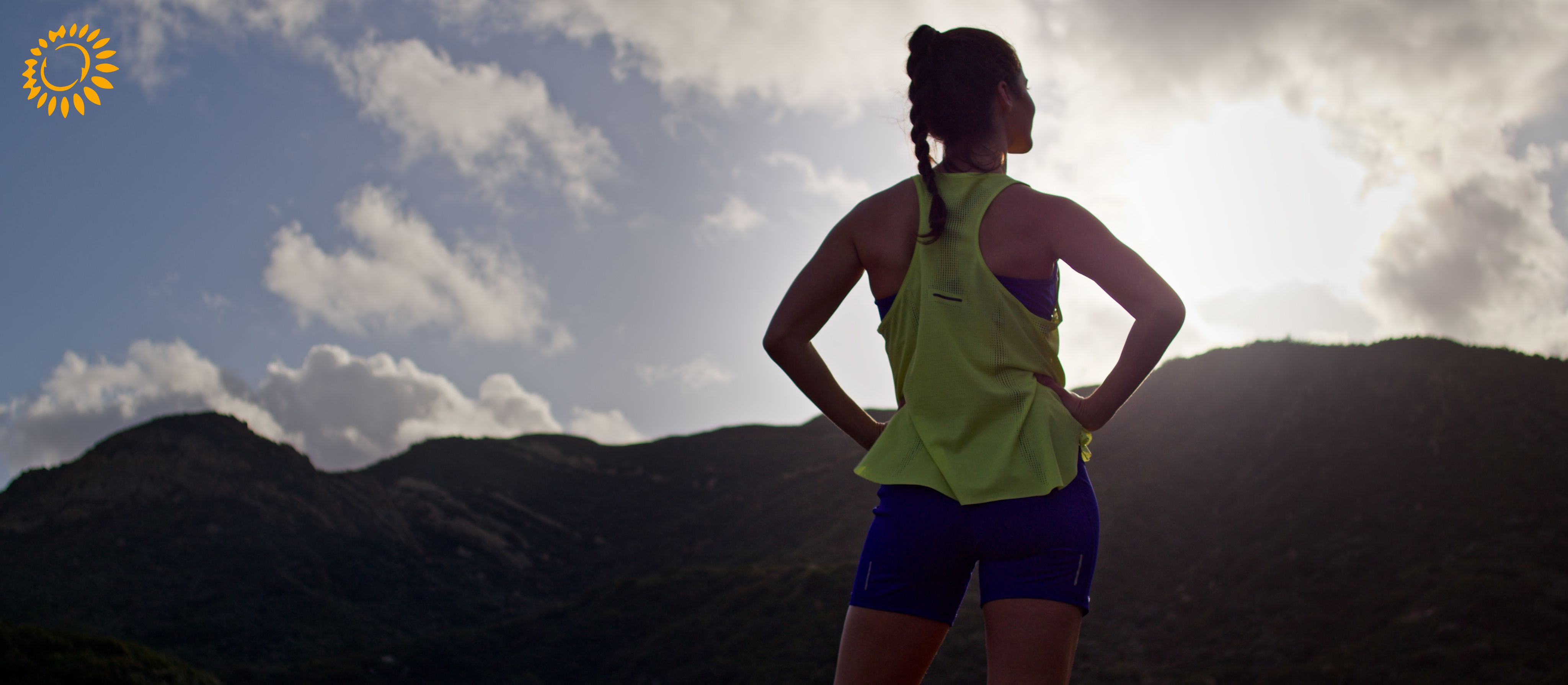 Woman looks out over a cliff sunset wearing ASICS sustainable apparel.